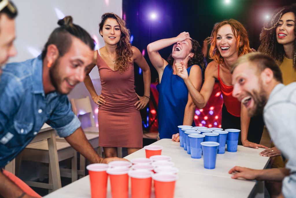 Glückliche Freunde, die in einer Cocktailbar Bier-Pong spielen